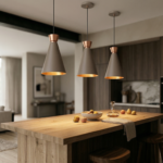 Esta imagem apresenta uma moderna cozinha de conceito aberto e área de estar com um design elegante e acolhedor. No centro, uma ilha de cozinha de madeira robusta é iluminada por três luminárias pendentes em forma de cone, com exterior cinza e interior dourado radiante. Sobre a ilha, há uma tigela de cerâmica com pêras e maçãs, um decantador de vidro, e um pano de linho dobrado. Dois banquinhos de madeira rústica estão posicionados sob a ilha. O fundo da cozinha exibe armários de madeira escura e uma bancada de mármore branco com eletrodomésticos embutidos, incluindo um forno e uma cafeteira. À esquerda, a área de estar é visível com um sofá bege confortável, uma mesa de centro com livros, e uma grande janela de vidro que se abre para uma vista externa de folhagem verde. O espaço tem um piso de madeira clara e um tapete de texturizado, criando uma atmosfera convidativa e luxuosa.